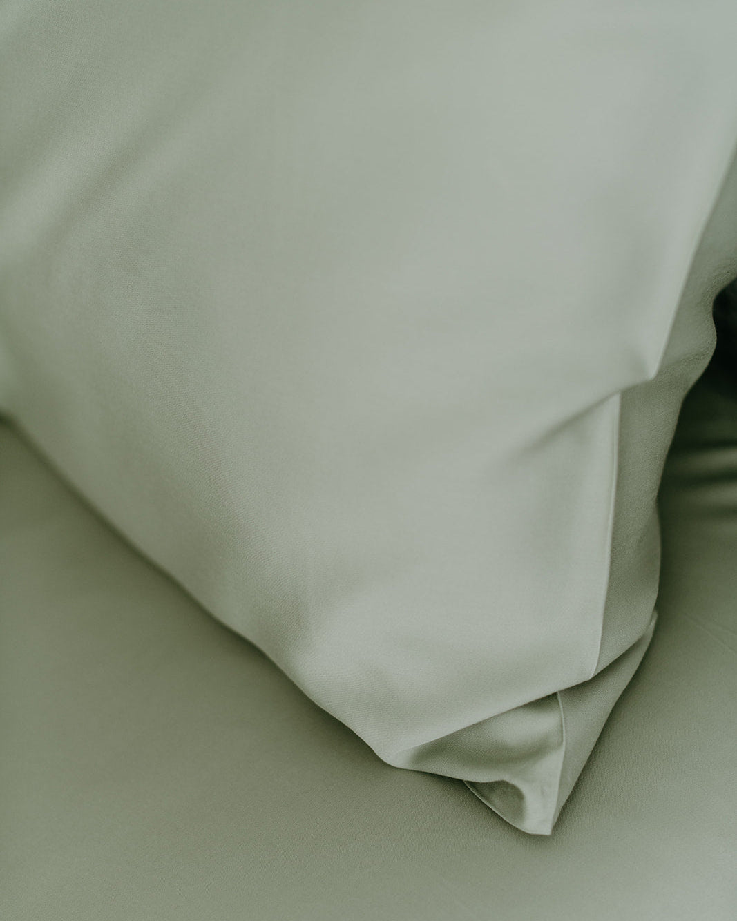 Close-up of a French Sage, light green pillowcase on a matching fabric background