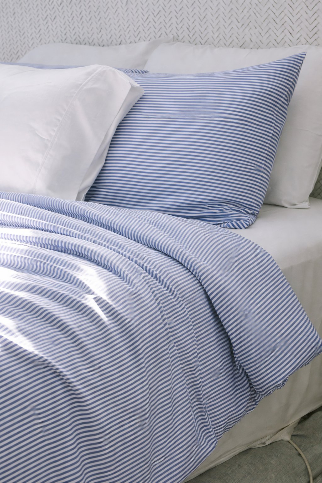 Simple white bed with St Tropez stipe pillowcases and duvet